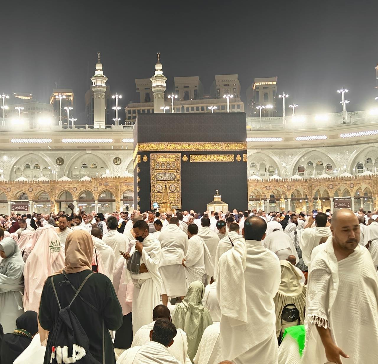 A large crowd of pilgrims at the Kaaba in Mecca during a religious gathering at night.